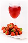 Fresh Strawberrys and glass of juice set against a plain background