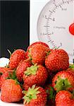 Fresh Strawberrys and wieght scales set against a plain background