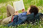 guy laying on the grass and reading a book