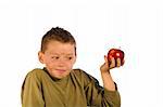 Very dirty young boy holding an apple and looking embarrased. Studio shot isolated on a white background.