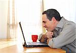 Man sitting at his desk with a laptop looking happy