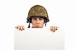 Serious soldier girl holding advertising space on white background