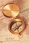 Antique brass compass over old Alaska map
