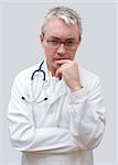 pensive doctor in glasses with stethoscope looking to the camera