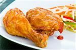 Fried chicken covered with tomato sauce - a caribbean speciality, served with grated vegetables. Shallow DOF.