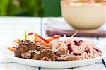 Caribbean style curried Oxtail served with rice mixed with red kidney beans. Dish accompanied with vegetable salad. Shallow DOF.