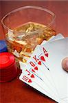 Poker player with cards and whiskey and chips