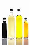 Several bottles of olive oil and vinegar reflected on white background