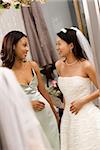 Asian bride and African-American bridesmaid talking to each other.