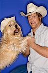 Fluffy brown dog and male Caucasian young adult wearing cowboy hats.