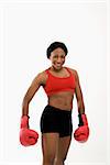 African American young adult woman wearing boxing goves smiling at viewer.