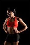 Smiling African American young adult woman in athletic apparel with hands on hips.