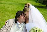 Recently married pair sits on a grass in park