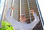 Triumphant businessman in the city raising arms in victory