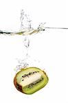 a kiwi fruit is falling in water with a big splash and a lot of water drops