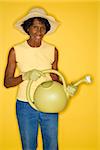 Mature adult African American female holding watering can.