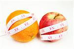 Measurement tape wrapped around red apple and a orange - health, diet