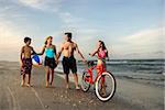 Caucasian family of four walking on beach.