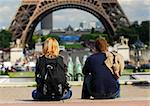 Young tourist couple sitting in front of Eiffel tower in Paris France