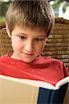 Caucasian pre-teen boy reading book.