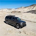 Four wheel drive truck on dirt road in barren landscape in Death Valley National Park.