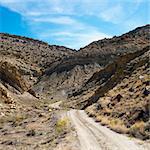 Dirt road winding through rocky desert cliffs of Cottonwood Canyon, Utah.