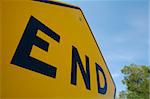 End Road Sign with Trees and Blue Sky Abstract