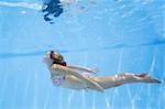 Pretty girl in bikini swimmking underwater in blue pool