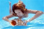 Woman in bikini underwater in pool with conch