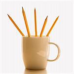 Five pencils in a coffee cup with pointed ends up.