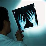 Asian American male doctor examining x-rays.