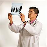 Asian American male doctor examining x-ray.