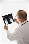 Caucasian mid adult male physician holding up hand xrays.