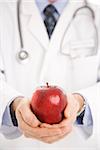 Caucasian mid adult male physician holding apple.