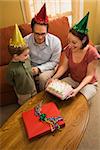 Caucasian boy in party hat with Birthday cake and family.
