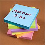 Stack of sticky notes with a meeting reminder.