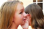 Two young teenage girls gossiping in school yard