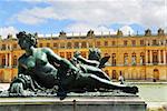 Bronze statue with royal palace in the background in Versailles, France.