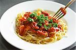 Plate of spaghetti with tomato sauce on a white plate.