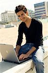 Happy confident man working with a computer outdoor at the beach