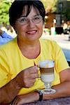 Happy mature woman in outdoor cafe holding a coffee