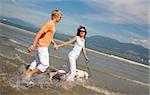 young couple walking in water with dog