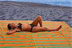 Femelle afro-américaine se détendre et prendre un bain de soleil par la mer