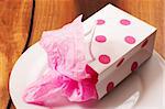 Pink colored polka-dot gift bag lying on white plate