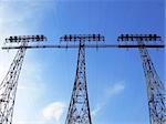 Three power pylons towering under the blue sky