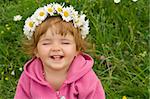 Happy laughing girl with daisy wreath on the spring meadow