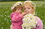 Woman and her baby girl looking at a beautiful daisy bouquet they just picked from the meadow