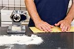 A Male making pasta on the counter in the kitchen.