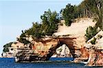 A rock with a hole above the lake in pictured rocks park.