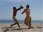 2 men playing volleyball on the beach
